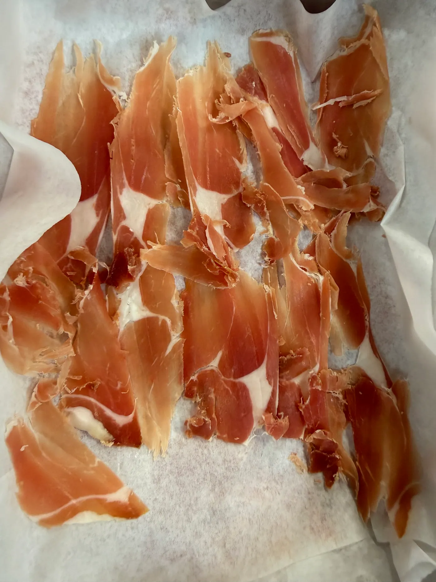 Thin slices of cured ham laid out on paper